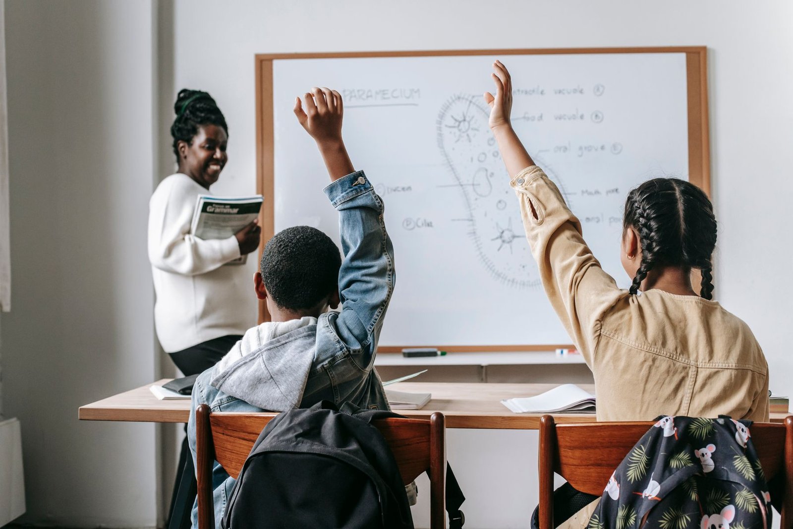 A Black teacher leading elementary students in a classroom